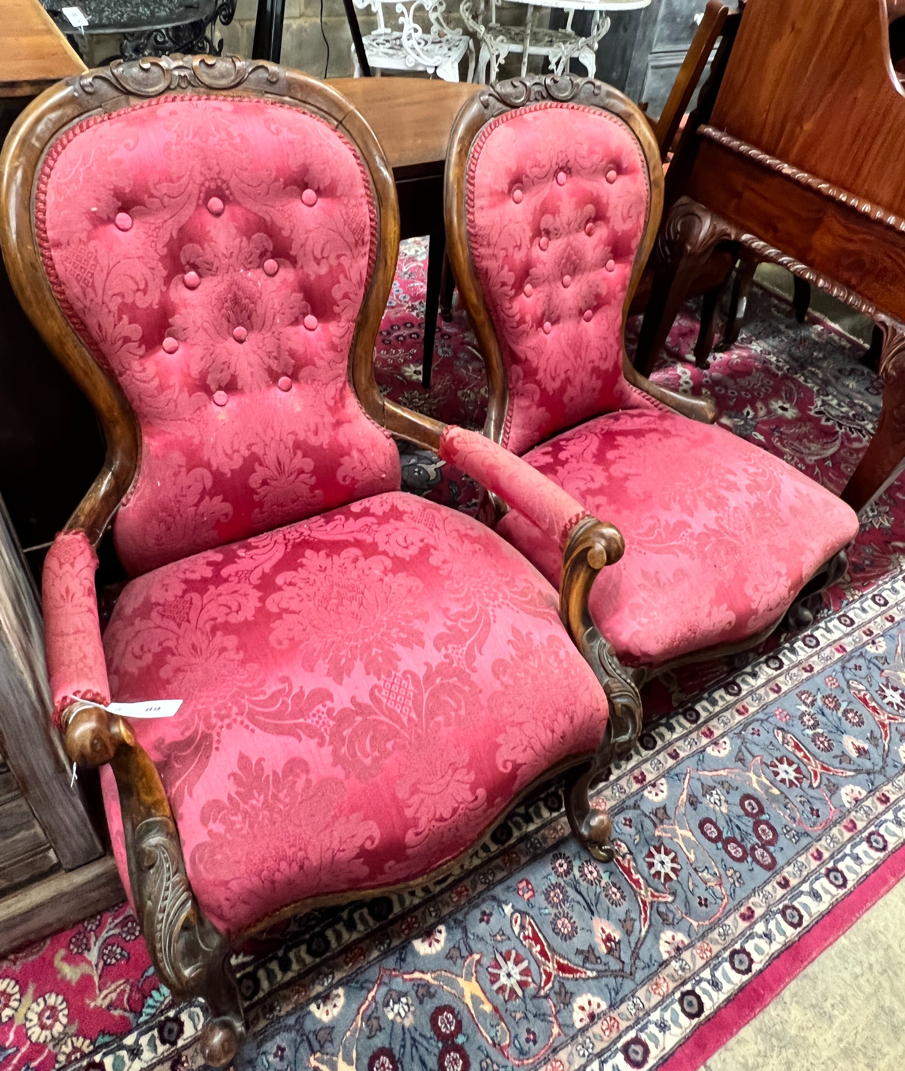 A pair of Victorian walnut spoon back upholstered chairs, one with arms